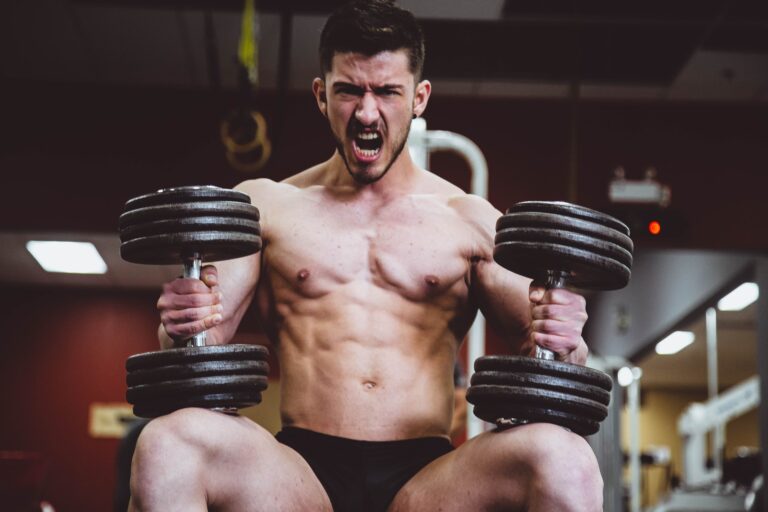 Bare-chested athlete working out with dumbbells