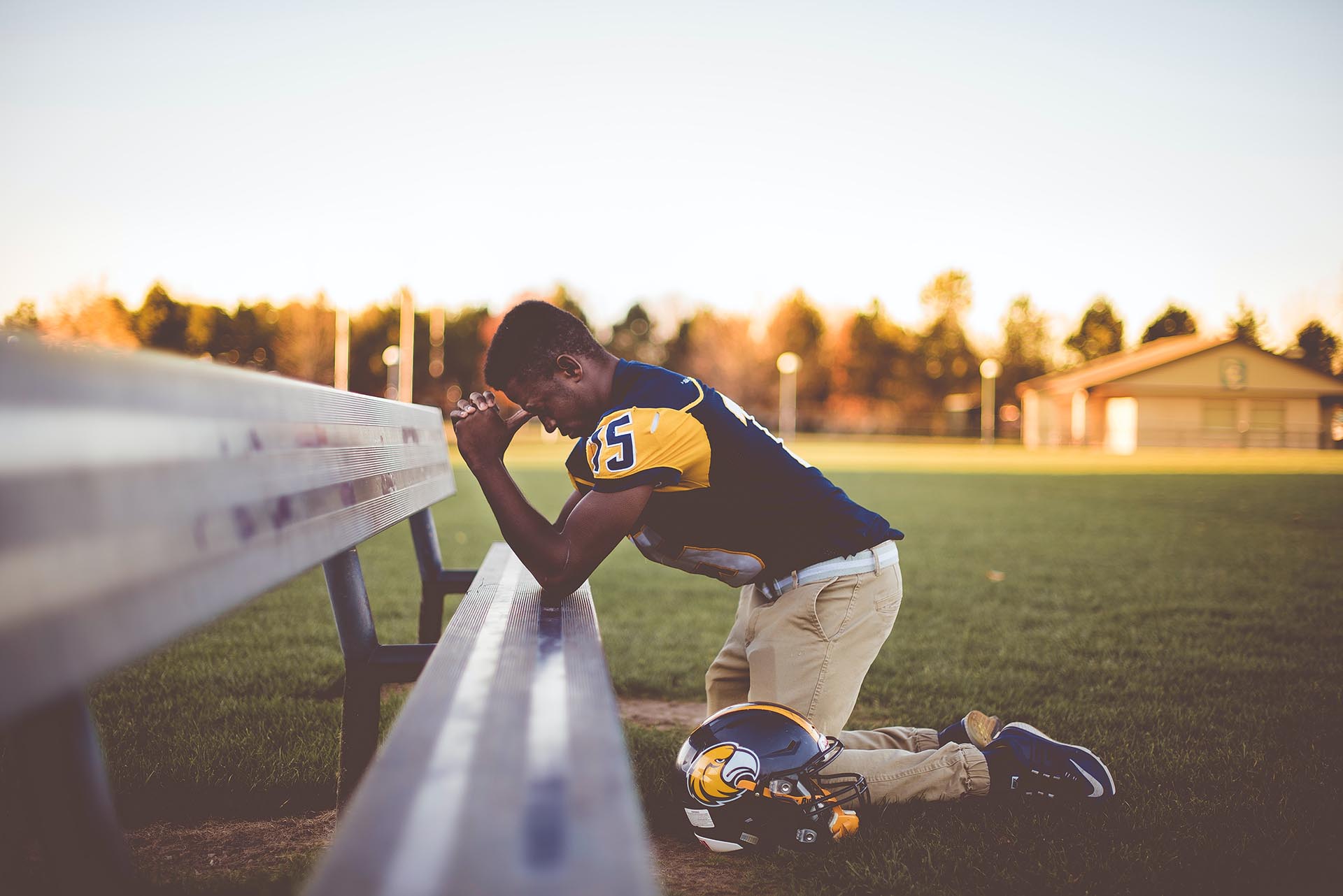 Student in football jersey praying at what could be a school event